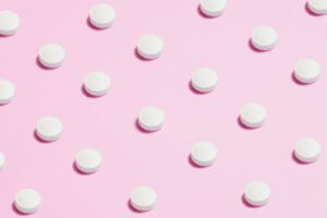 white round pills against a pink backdrop